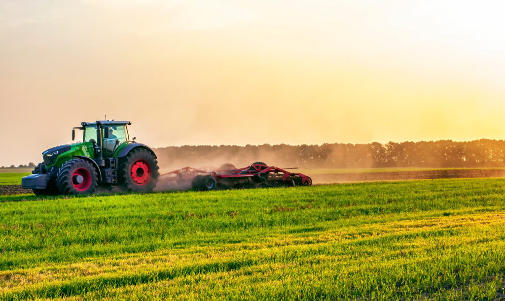 Image of a tractor working a field utilizing its agricultural hydraulic oil